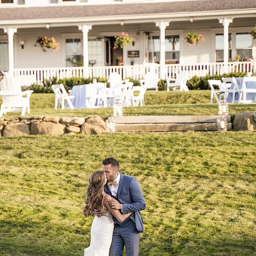 A couple is embracing in front of a large inn with a sign that reads 