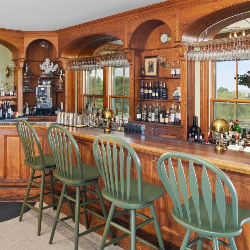 A cozy cafe with warm wood tones, arched shelves, colorful stools, and string lights along a curved bar counter.