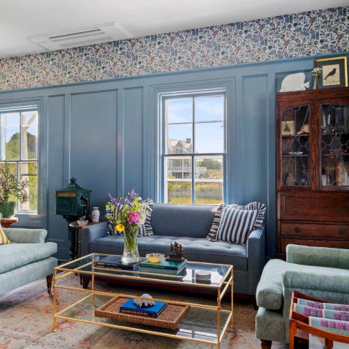 A cozy living room with a blue-gray sofa, armchairs, a coffee table, a brick fireplace, and warm lighting in a traditional space ending with a homey vibe.